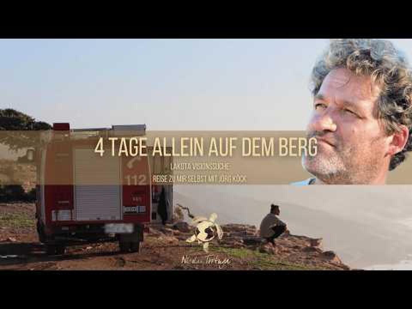 Ein Feuerwehrauto ist auf einem felsigen Berg geparkt, mit einem nachdenklich blickenden Mann in der oberen rechten Ecke. Der überlagerte Text auf Deutsch lautet: 4 Tage allein auf dem Berg. Lachs versuchsfahrt. Reise zum Selbst mit Joschko.