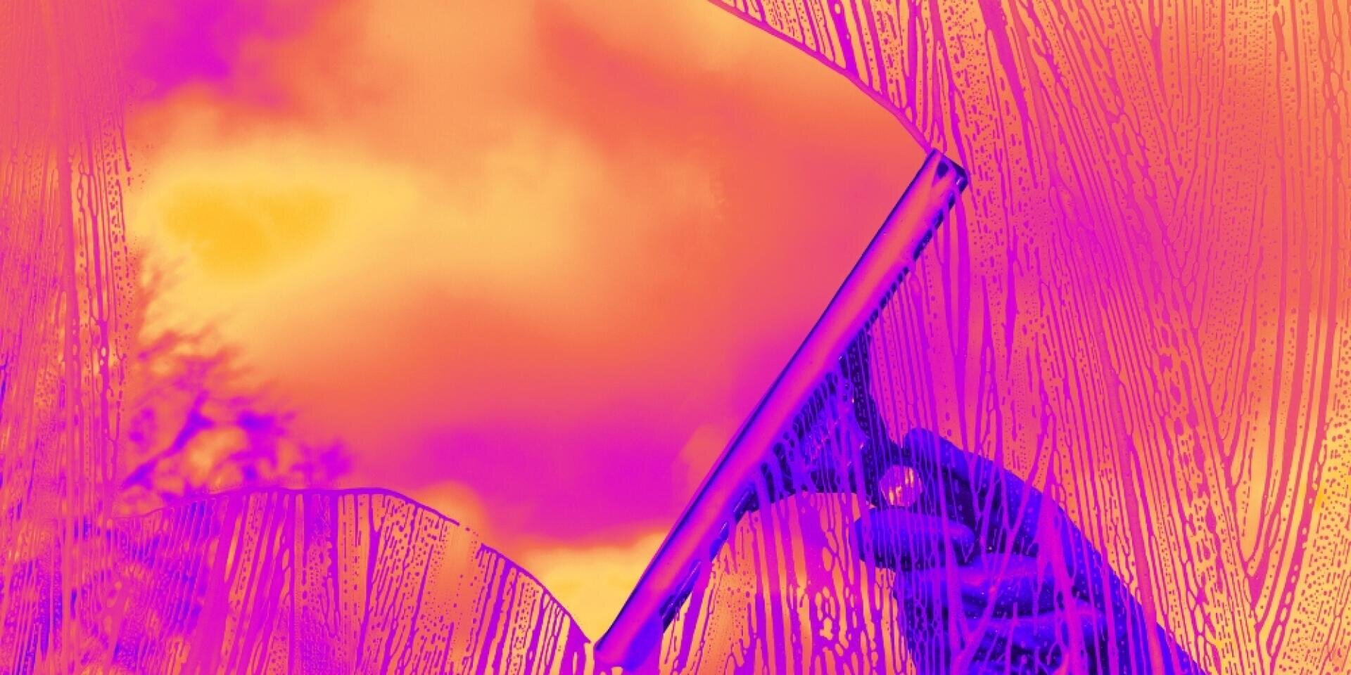 Eine Hand wischt mit einem Wischer ein Fenster und gibt den Blick auf einen hellen Himmel mit Wolken frei. Das Bild hat einen lebendigen lila und orangefarbenen Farbfilter, der einen surrealen, farbenfrohen Effekt erzeugt.