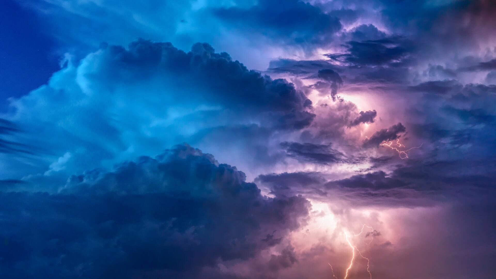Blitze erhellen dunkle, stürmische Wolken in Blau- und Violetttönen.