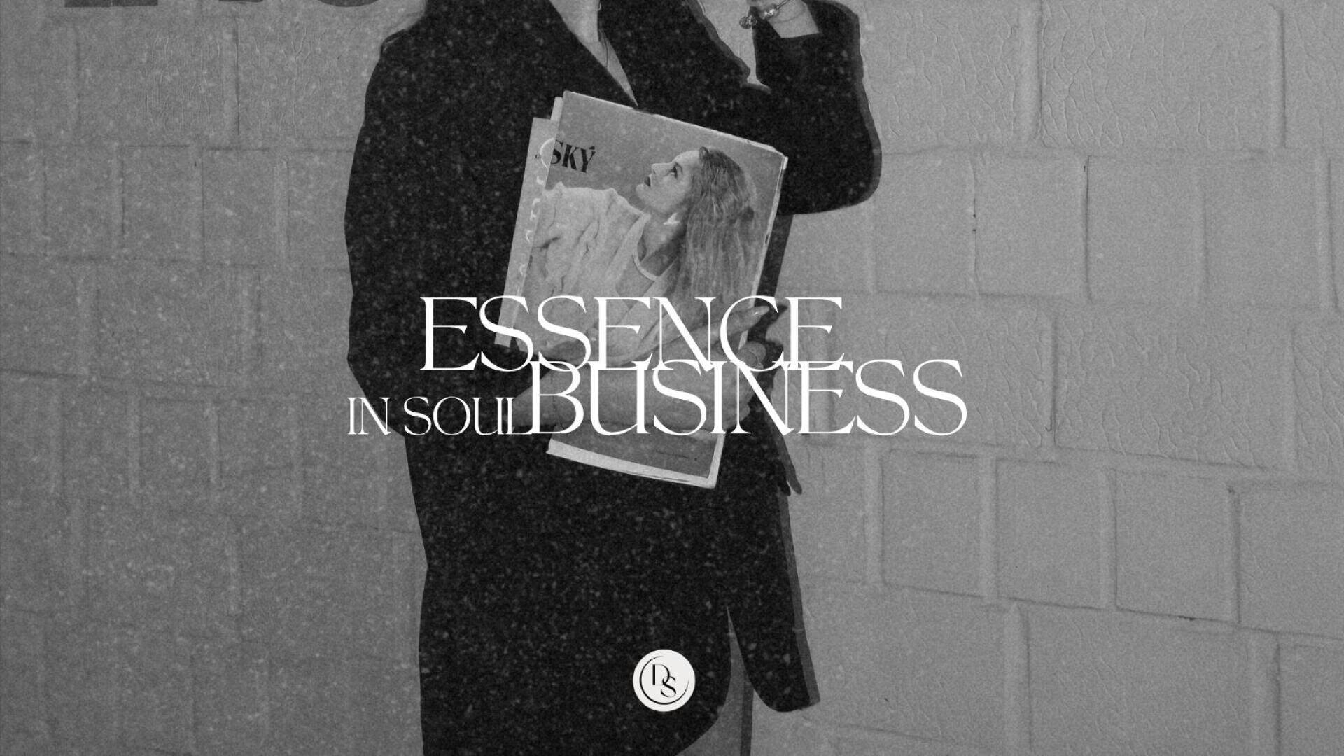 Eine Person in einem dunklen Mantel hält eine Zeitschrift mit dem Foto einer Frau auf dem Cover. Das Bild ist in Schwarz-Weiß gehalten, und der Text ESSENCE IN SOUL BUSINESS ist in großen, eleganten Buchstaben darübergelegt.
